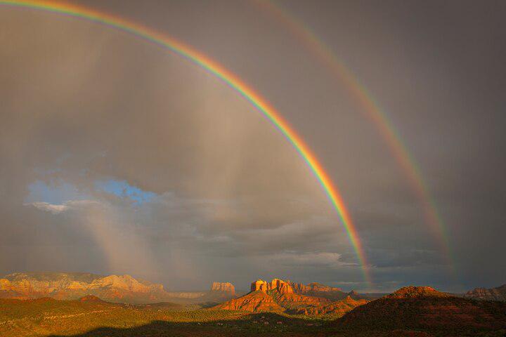A magnificent double rainbow arcs over red rocks near Sedona, Arizona.