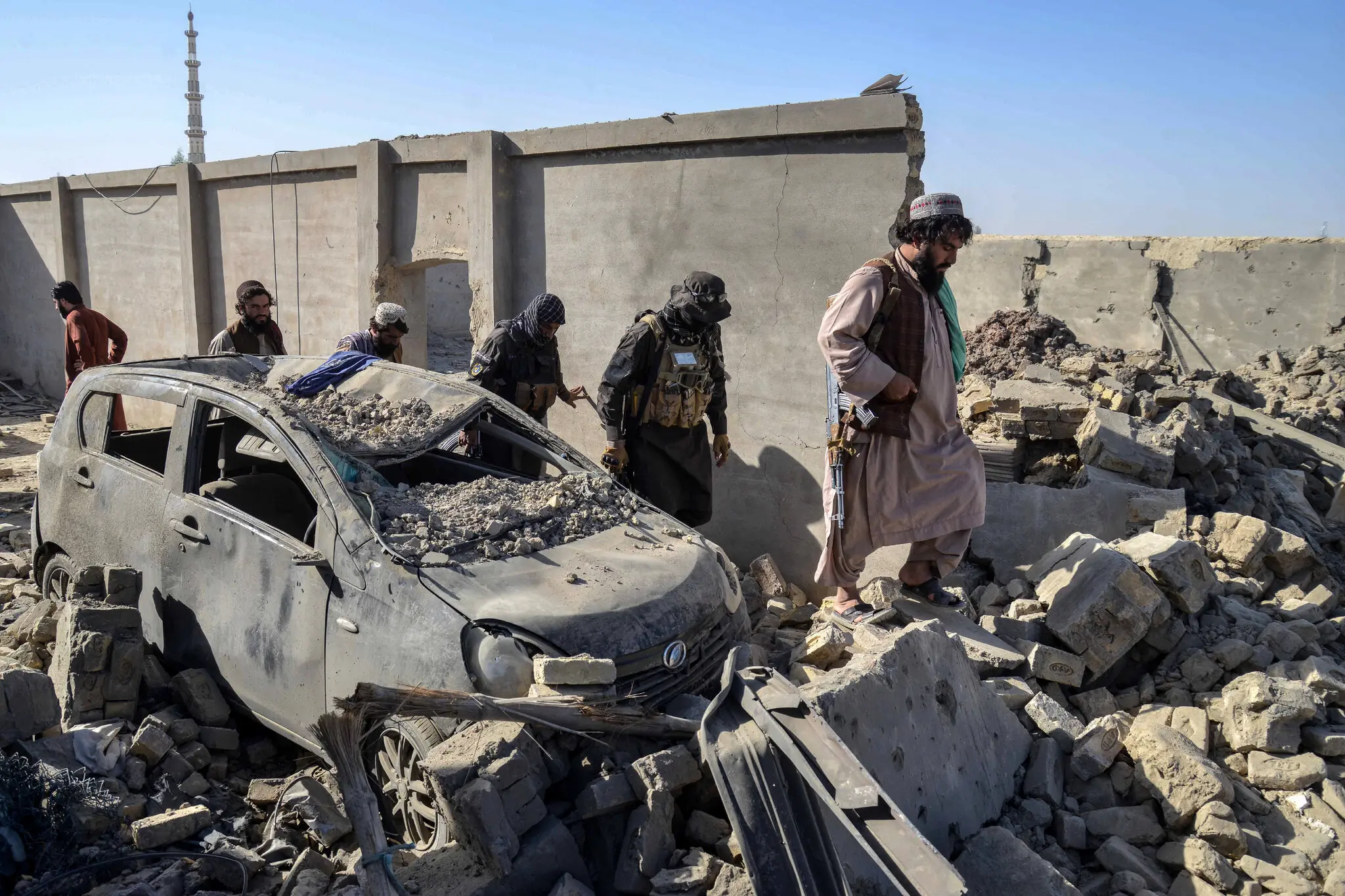 Taliban security personnel walking past a destroyed car in Afghanistan’s Kandahar Province on Thursday, a day after cross-border clashes between Afghanistan and Pakistan.
