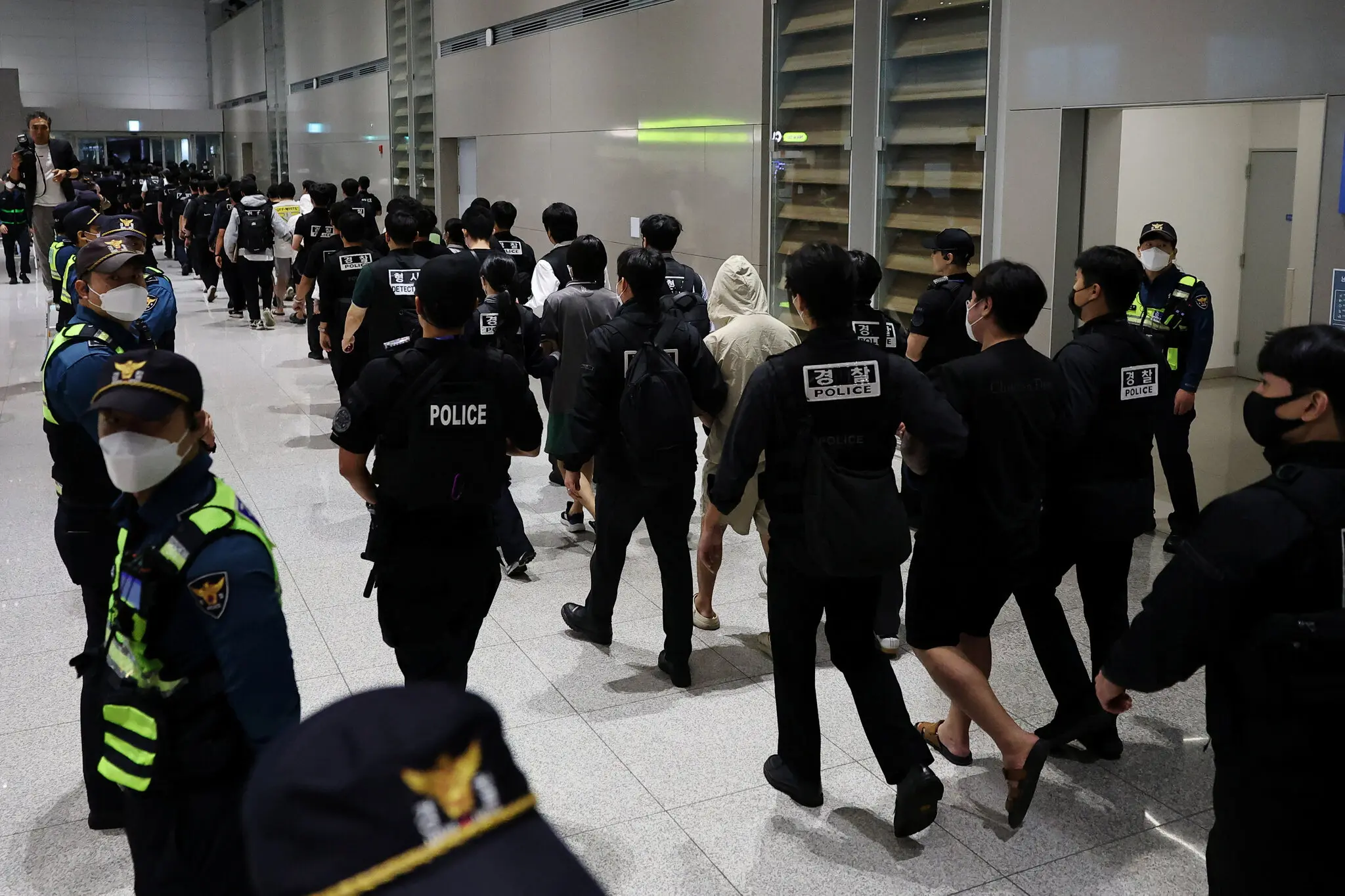 Police escorting South Koreans accused of working in online scam centers in Cambodia, upon their arrival at Incheon airport in Seoul in October.