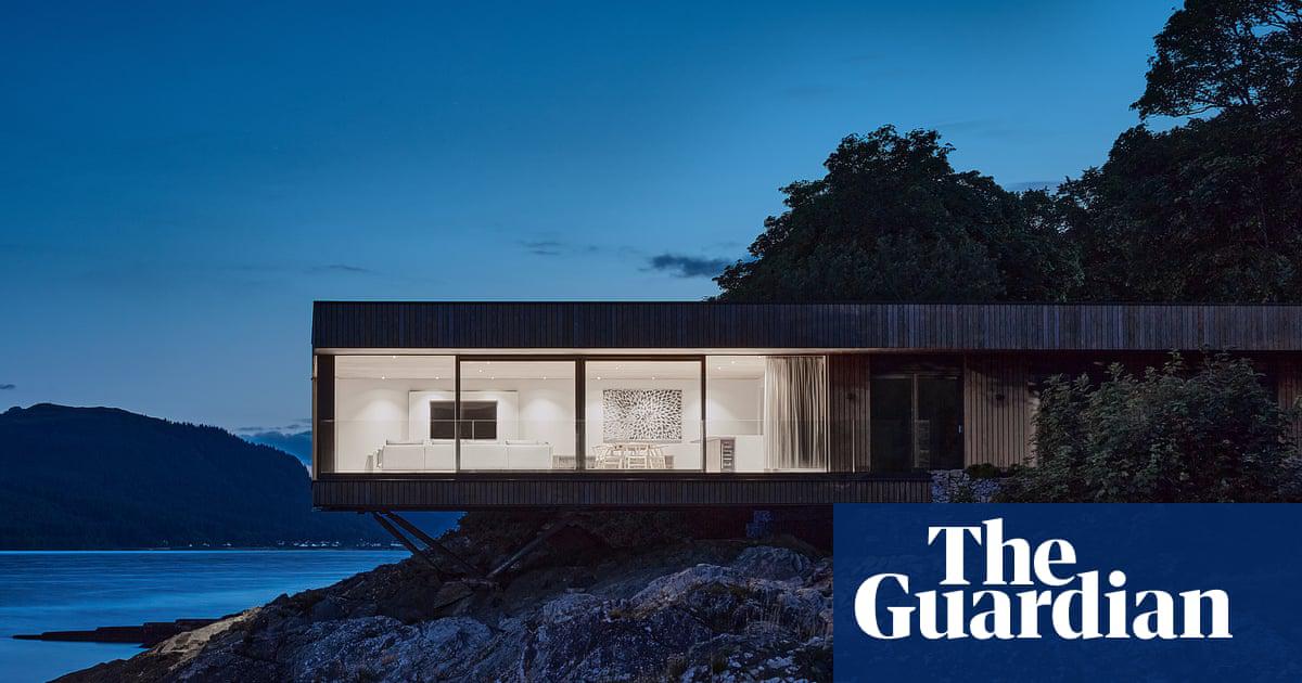 The house is a low-slung box, with a cantilevered living area that juts out over the rocks below.