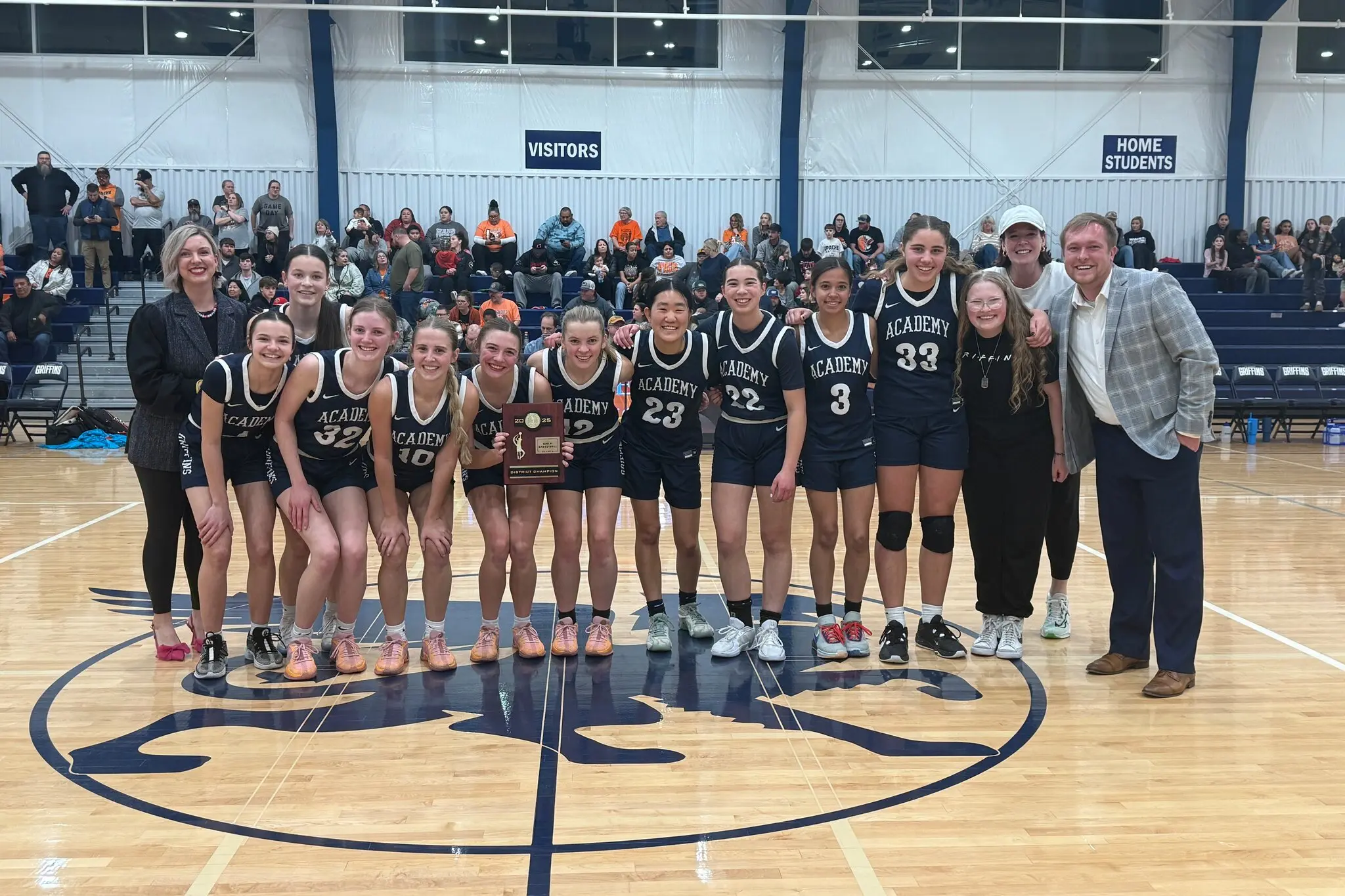 The girls high school basketball team of the Academy of Classical Christian Studies, displaying their districts trophy, before they returned it. Their coach, Brendan King, stood on the far right.