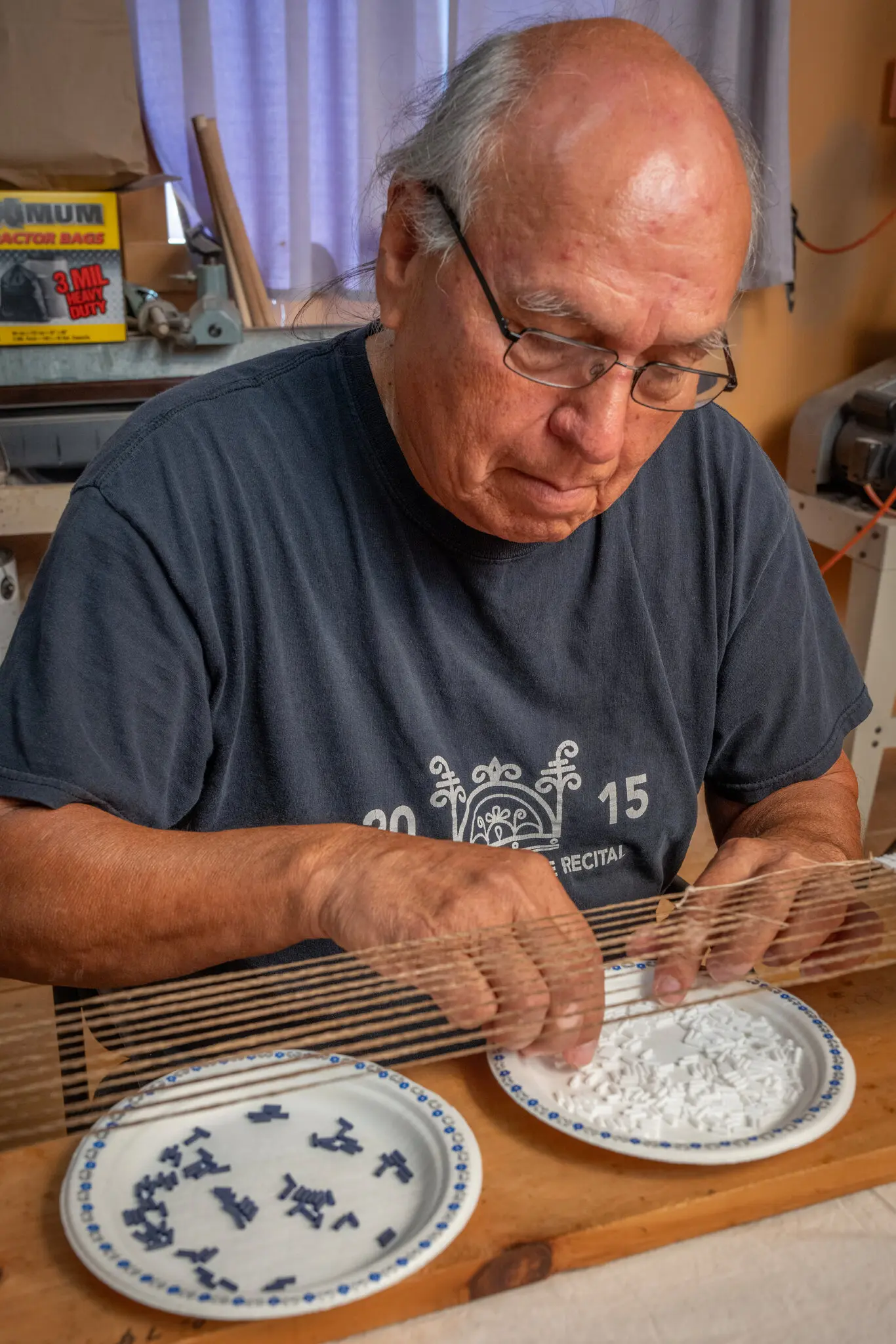 Ken Maracle, an artist who is a member of the Cayuga Nation, uses a needle to thread a glass bead for a wampum belt at his studio on Manitoulin, an island just off the Canadian coast of Lake Huron.