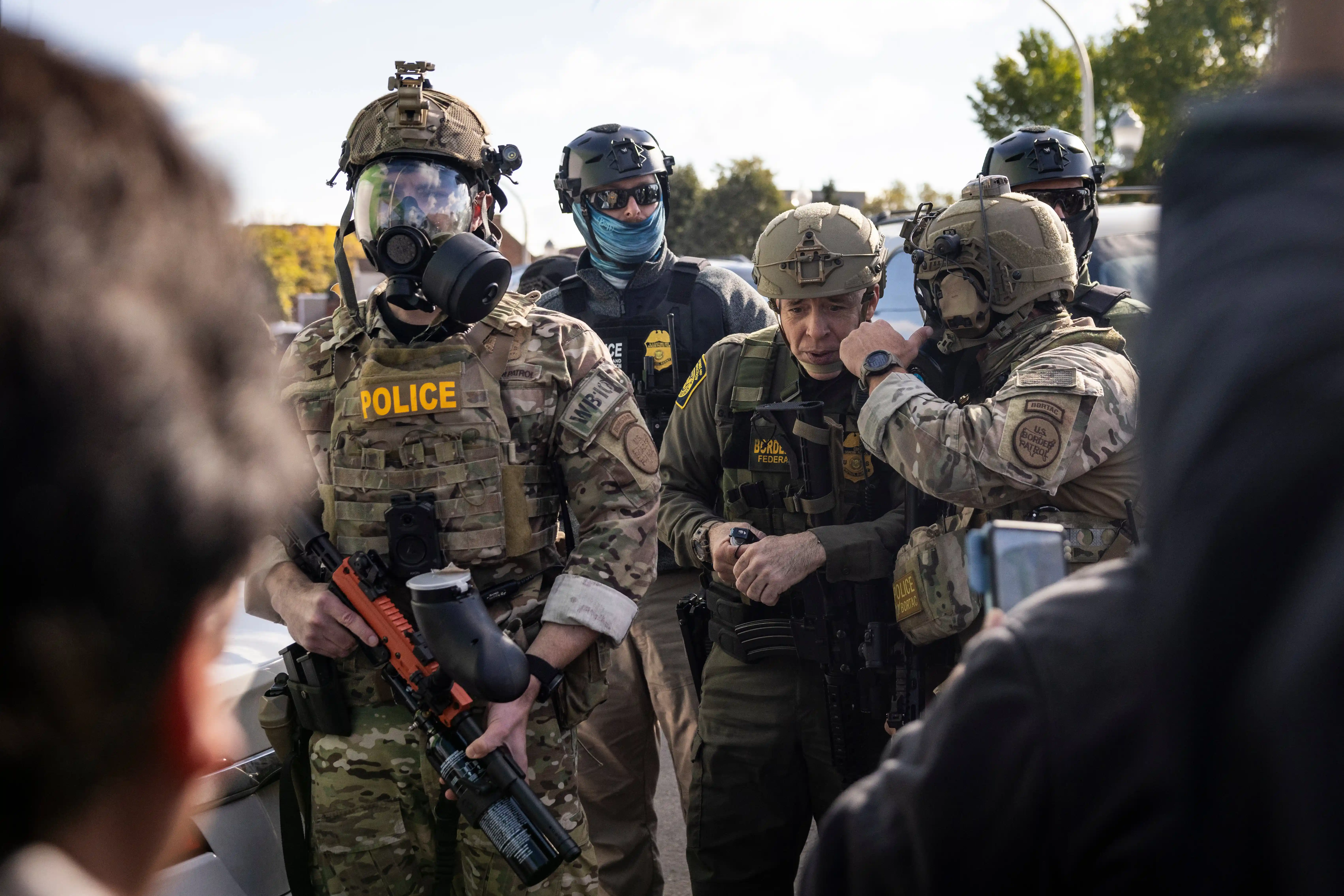 Gregory Bovino, a senior Border Patrol official, threw a tear gas canister at a large group of Chicago residents on Thursday. Tensions escalated after officials arrested a security guard in a mall parking lot.
