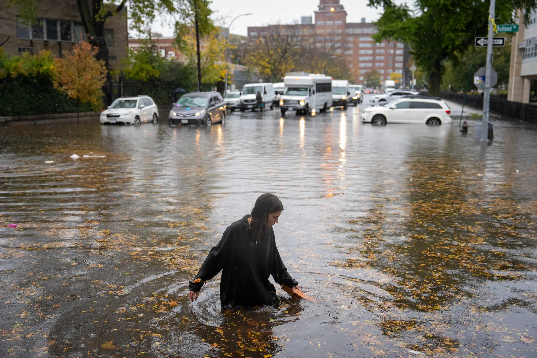 A woman attempting to clear the drains after flooding at the intersection of Kingston Avenue and Rutland Road in Brooklyn.