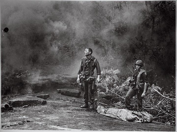 Two exhausted American soldiers stand next to a slain compatriot in Long Khánh, Vietnam, in 1966.