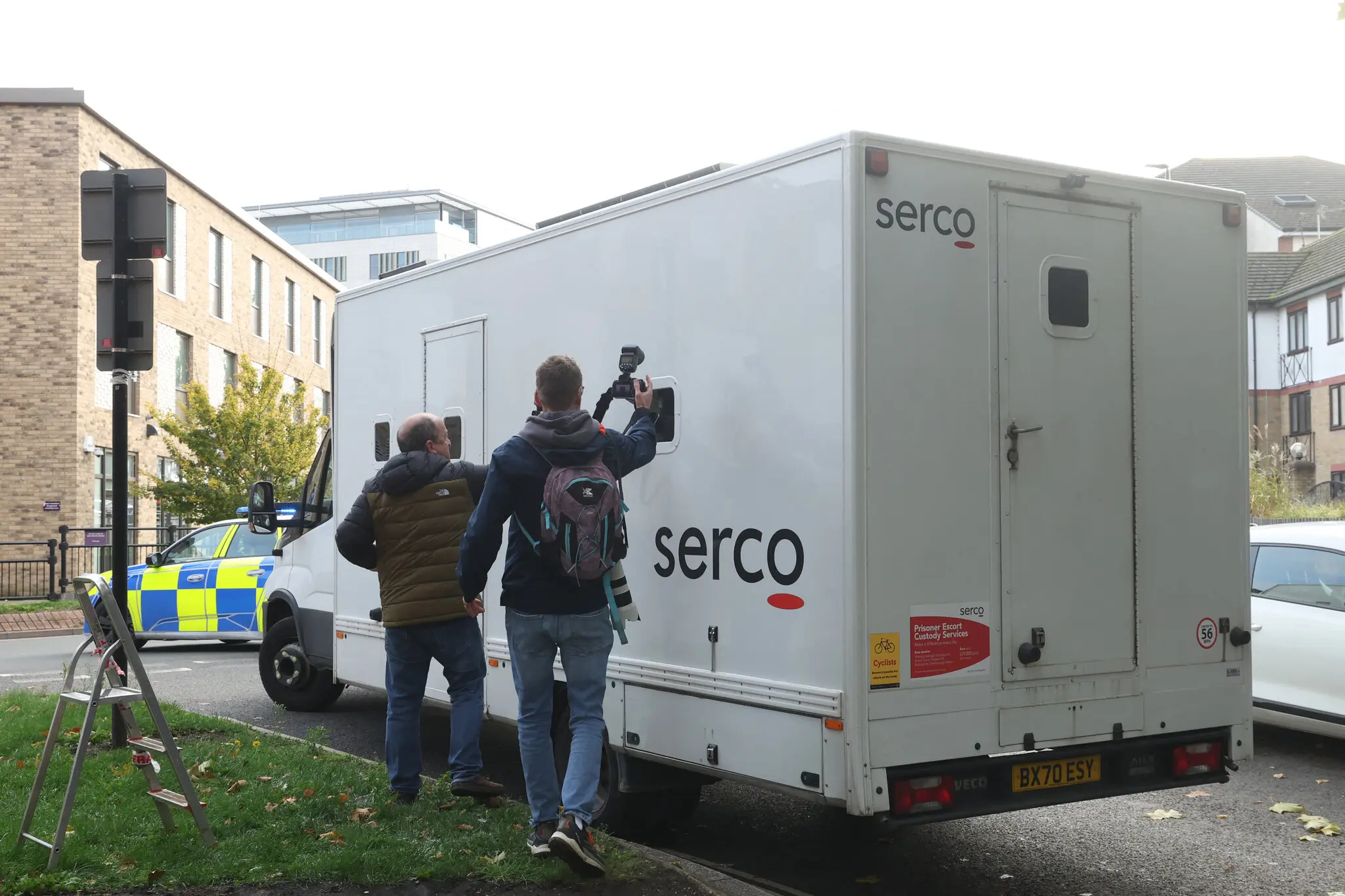 Photographers attempt to capture a picture of the suspected perpetrator of multiple stabbings on a train near Huntingdon, as a prison van leaves Peterborough Magistrates Court on Monday.