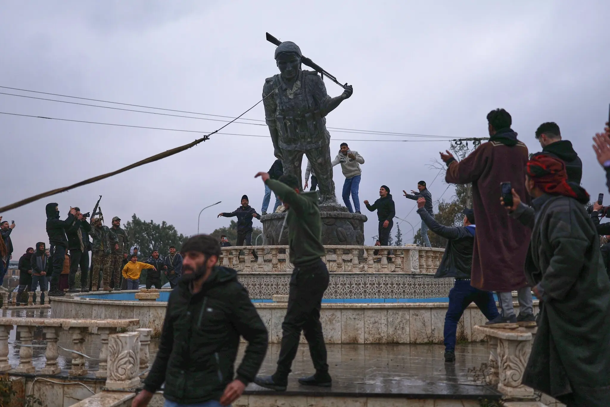 People toppling a statue of a female Kurdish fighter on Sunday in Tabqa, eastern Syria, after government forces captured the area.