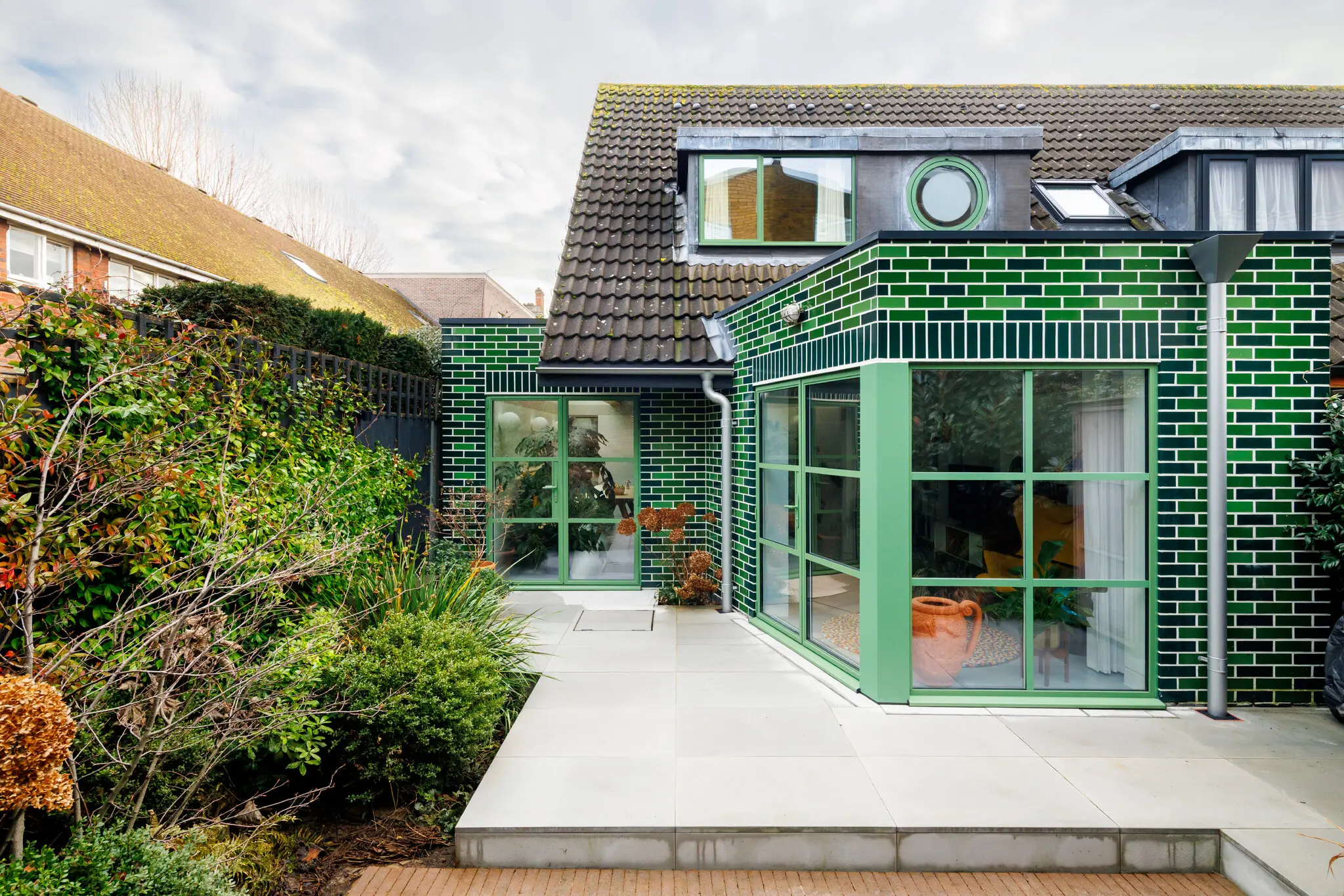 Seen from the backyard, the Jealous House is trimmed in green bricks that mark the places where it has been extended.