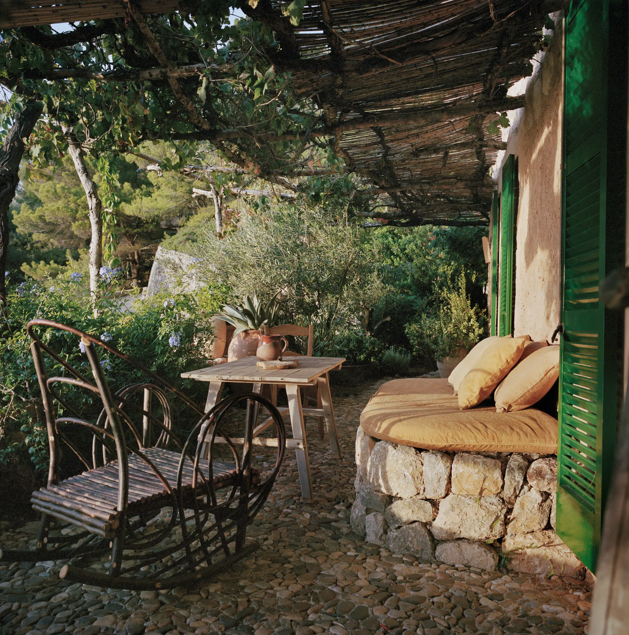 On one of the terraces of the interior designer François Champsaur’s home and studio on Majorca, a rocking chair in chestnut of his own design for Atelier Chatersèn, a naturally dyed cushion by Earth Core and an antique Majorcan table.